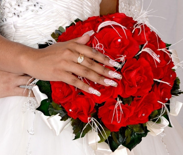Woman's hand holding a red rose, showcasing elongated white hand-drawn LT Glow handmade press-on nails