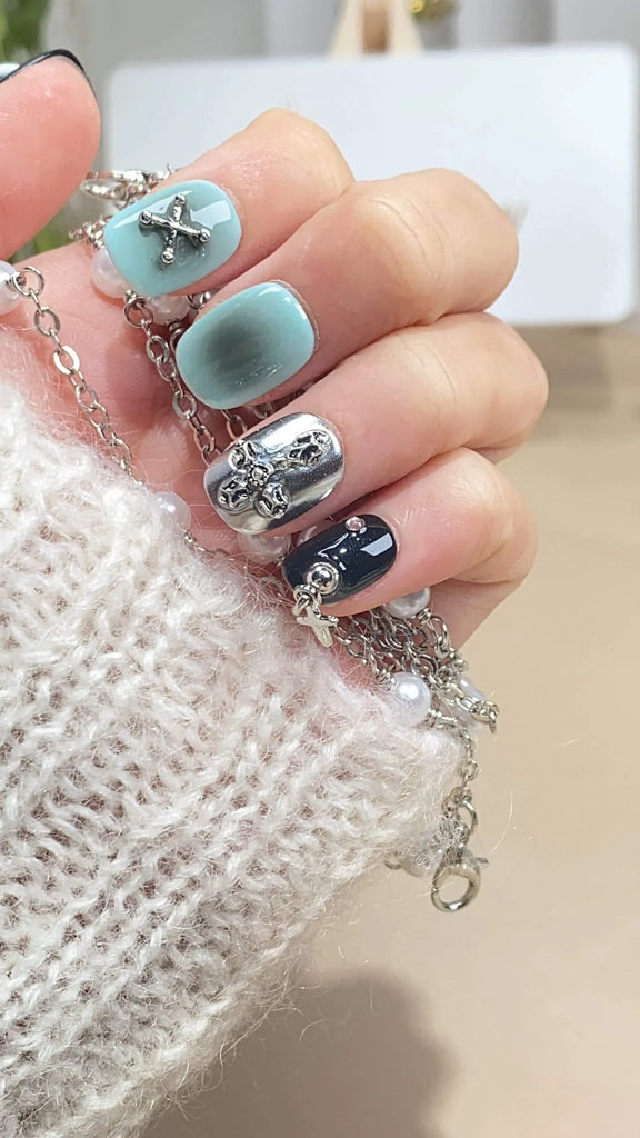 Elegant squoval press-on nails by LT-Glow with blue, black, and silver hues highlighted by unique 3D charms