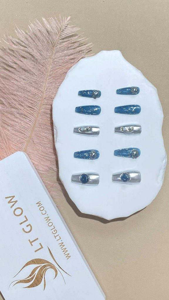 Coffin-styled fake nails from LTGlow, featuring a chic mix of blue and gray, enhanced by sparkling glitter, intricate charms, and shimmering crystals