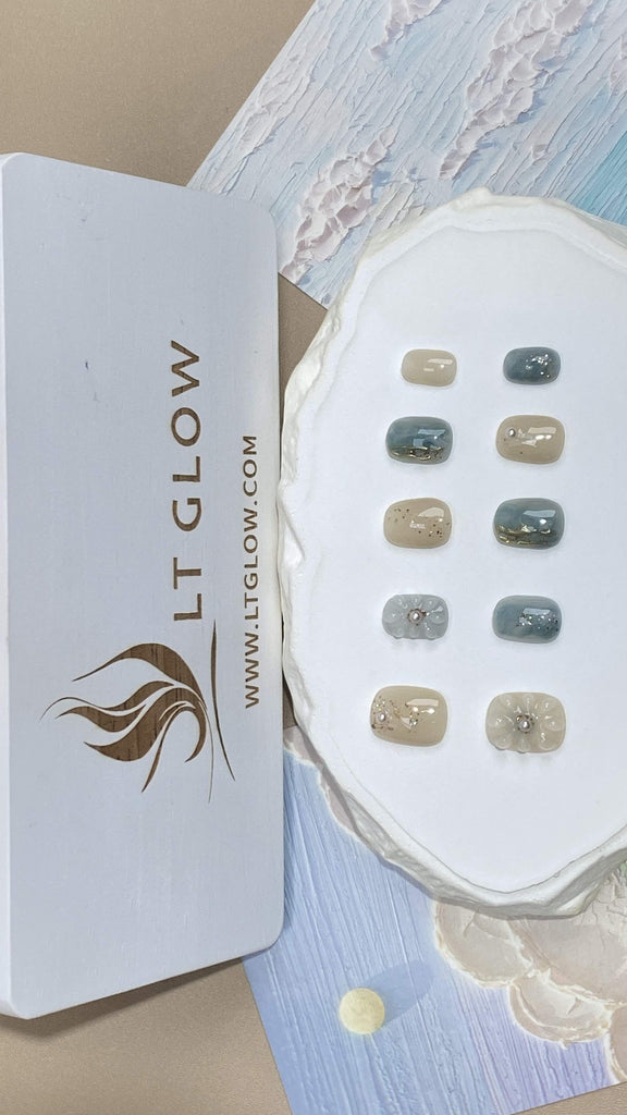 Squoval-styled fake nails from LTGlow, showcasing a harmonious blend of blue and nude, embellished with sparkling diamonds, glitter accents, and radiant pearls for an elevated look