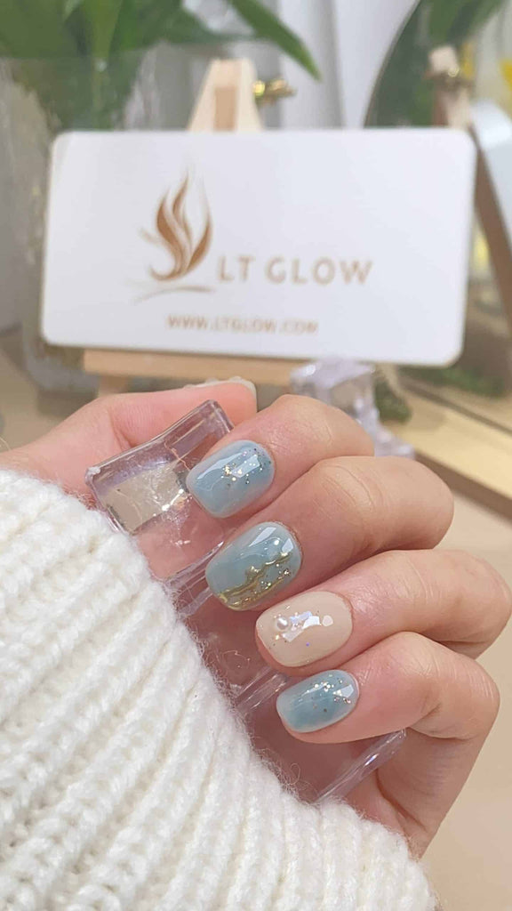 Handmade squoval press-on nails by LTGlow, featuring a serene blue combined with a subtle nude hue, adorned with radiant diamonds, shimmering glitter, and lustrous pearls