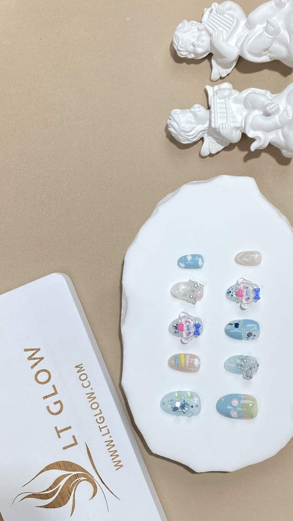 Chic handmade squoval fake nails from LT-Glow, transitioning from blue to pink to white hues, enhanced with shimmering pearl details and playful cartoon glitter