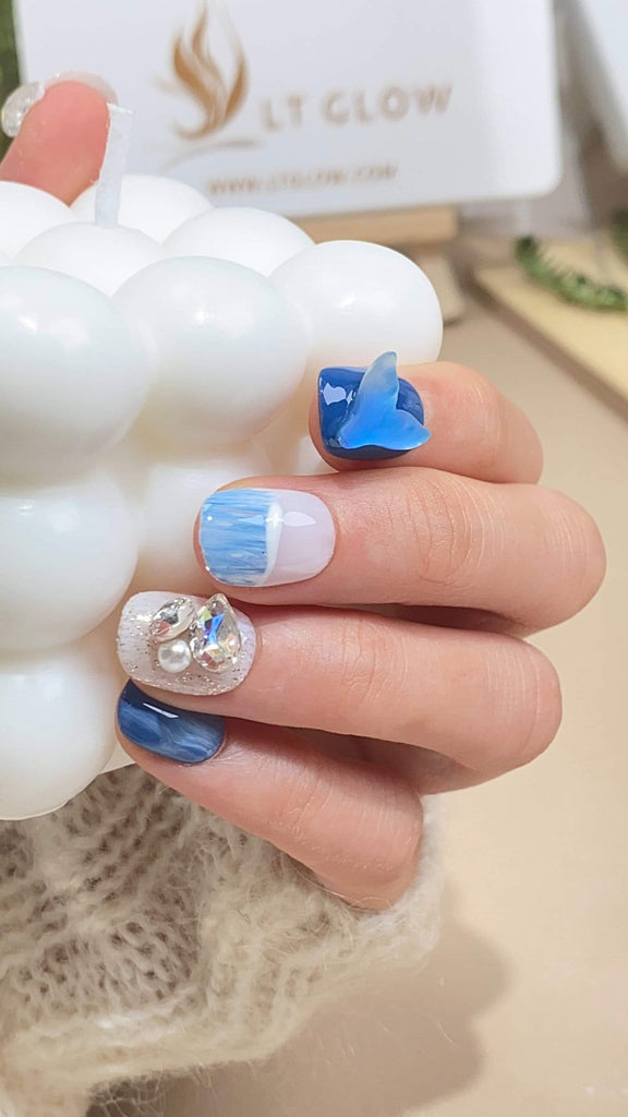 Dive deep into oceanic beauty with these blue and white squoval press on nails, meticulously hand-painted with a mesmerizing mermaid motif, adorned with shimmering diamonds and crystals for a dazzling acrylic nails design