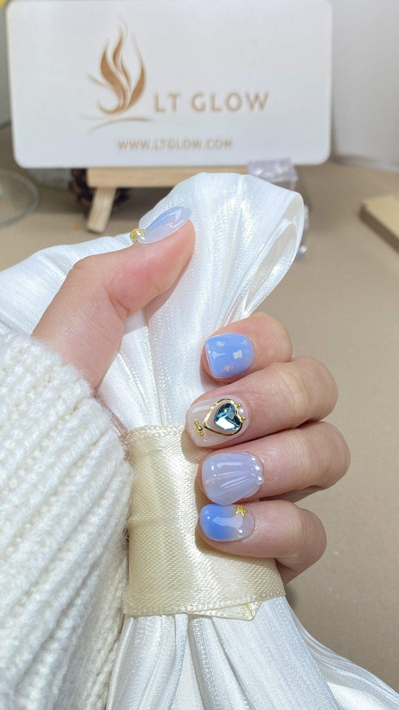 Handmade round press-on nails by LTGlow, showcasing a captivating blend of blue and white adorned with charms, shimmering diamonds, glitter, and lustrous pearls