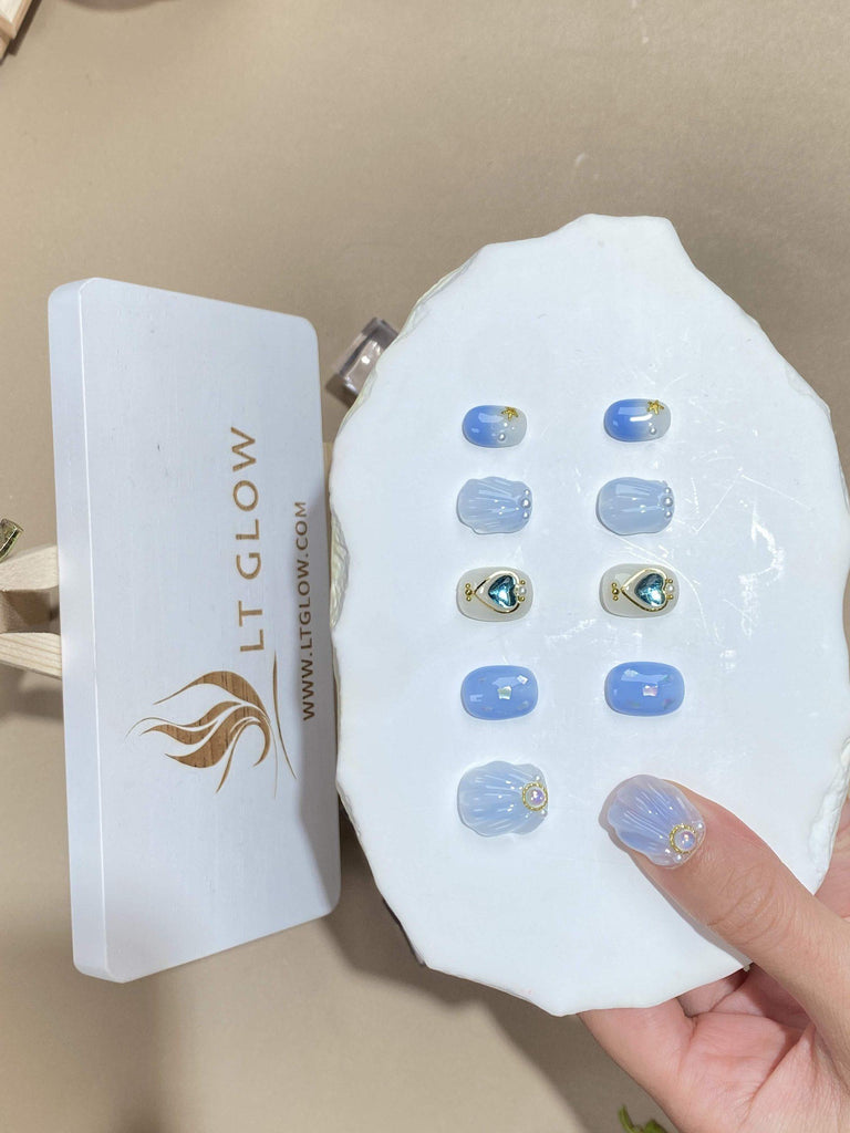 Round-styled fake nails from LTGlow, featuring a chic interplay of blue and white, enhanced by sparkling glitter, intricate charms, radiant diamonds, and pearls
