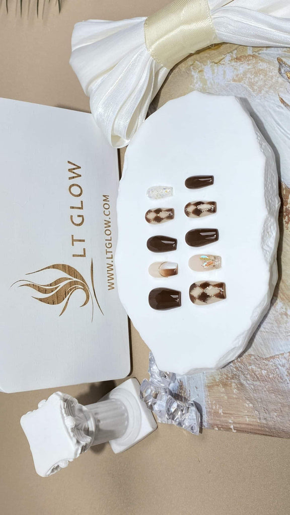 Coffin-styled fake nails by LTGlow, adorned with a brown nude base, glittering rhombus designs, and delicate charm embellishments