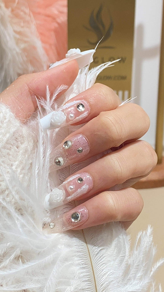Elegant press-on nails featuring a blend of white and nude hues with flower designs and a touch of glitter