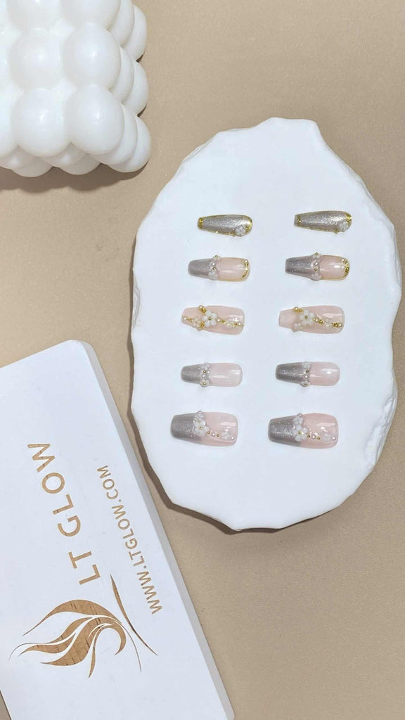 Elegant nude coffin nails by LT Glow, adorned with sparkling silver charms, delicate hand-painted flowers, and perfectly placed pearls