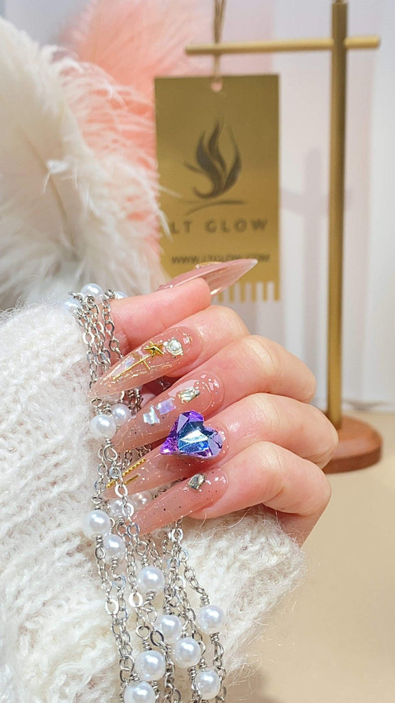 Handcrafted stiletto press-on nails by LTGlow, featuring a sophisticated nude design adorned with glitter, charms, and diamond embellishments