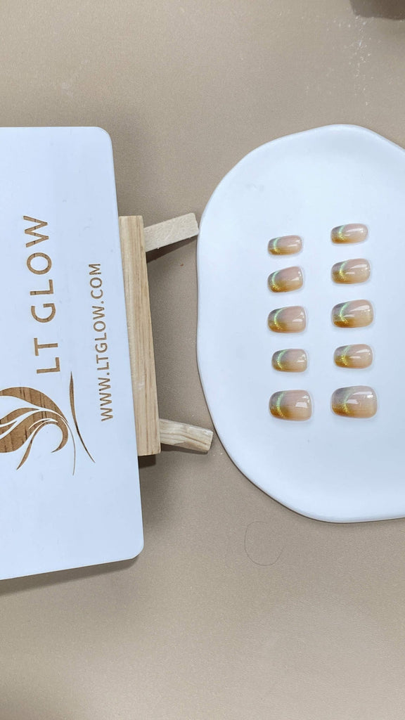 Squoval-styled fake nails from LT-Glow, capturing the warmth of orange, elevated with an enchanting cat-eyes effect and shimmering glitter highlights