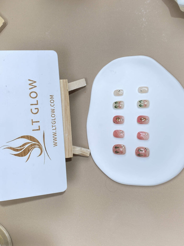 Squoval-styled fake nails from LTGlow, featuring a soft pink hue, complemented by intricate tulip designs and radiant diamonds