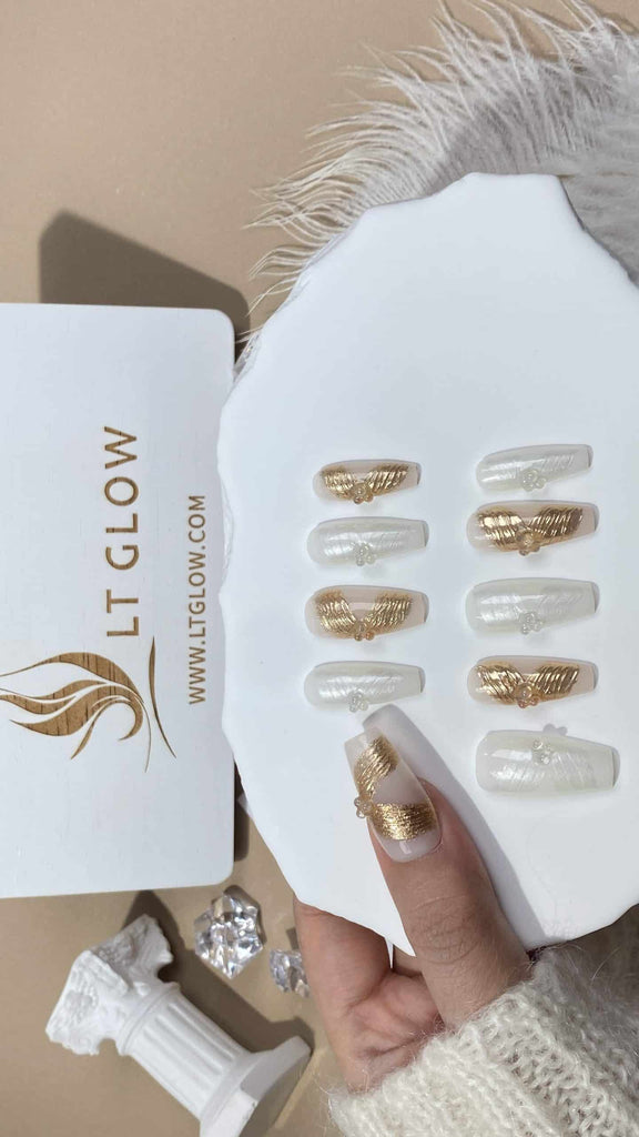 LTGlow's crafted fake nails in a coffin style, adorned with a pristine white base highlighted by gold ribbon accents