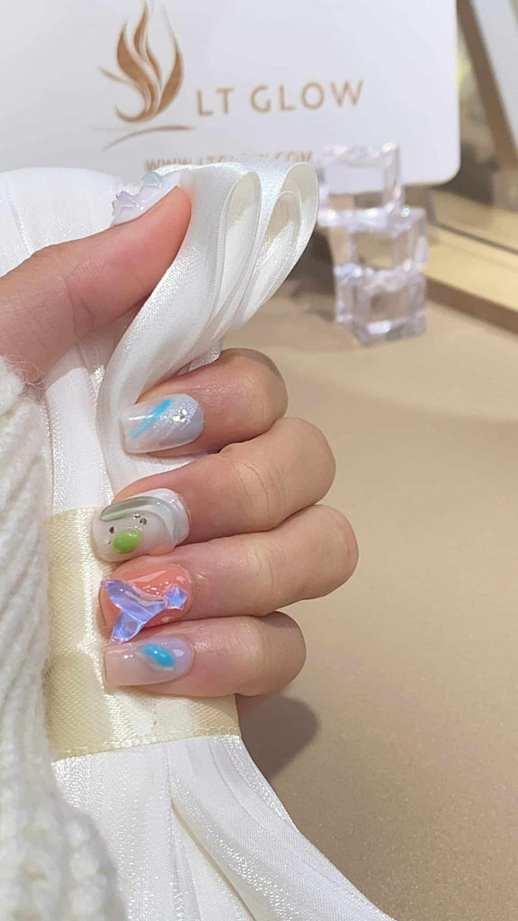 Ethereal white press-on nails featuring mermaid and tulip designs, meticulously hand-painted on a square finish
