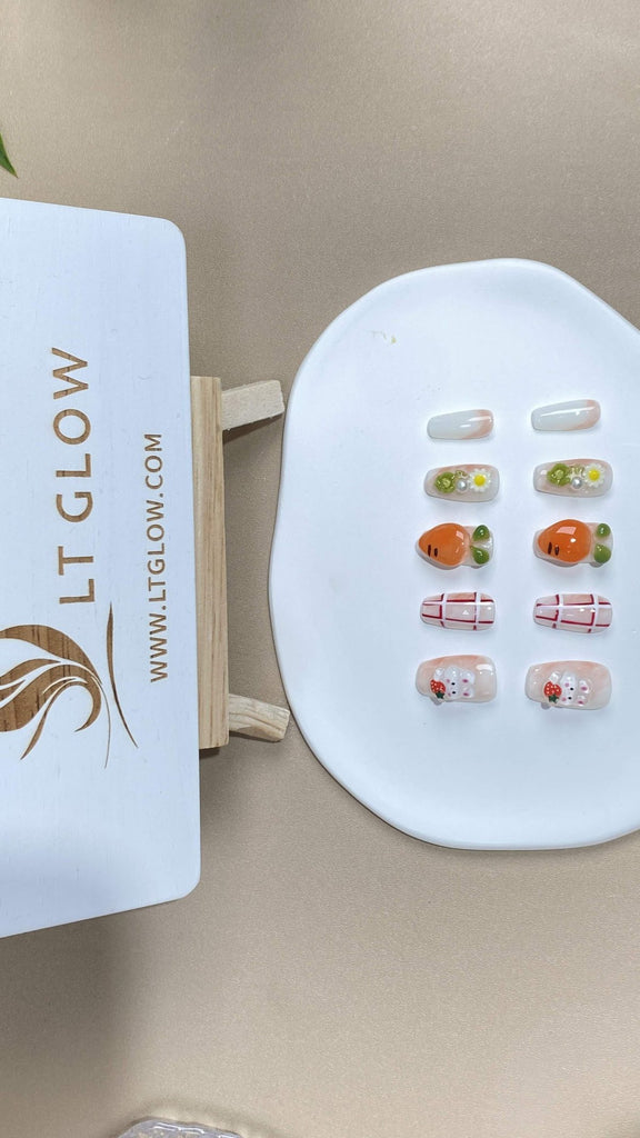 An adorable hand-painted rabbit nibbles on a carrot, set against a soft white and orange backdrop on these coffin false nails, further adorned with flowers and pearls. A whimsical touch to your artificial nails collection