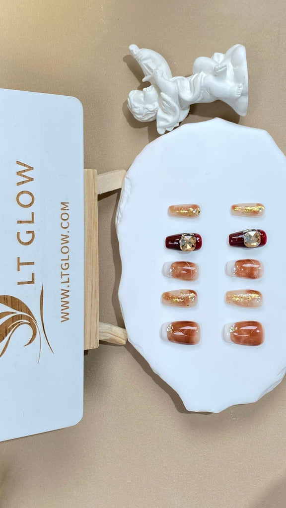 Handcrafted brown coffin nails from LT-Glow, radiating a luxurious gold sheen, intricately hand-painted with diamond and crystal designs, and finished with a layer of glistening glitter