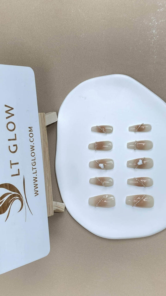 LTGlow's artisanal fake nails in a coffin design, adorned with a pink to nude gradient and detailed with pearl chains and heart motifs