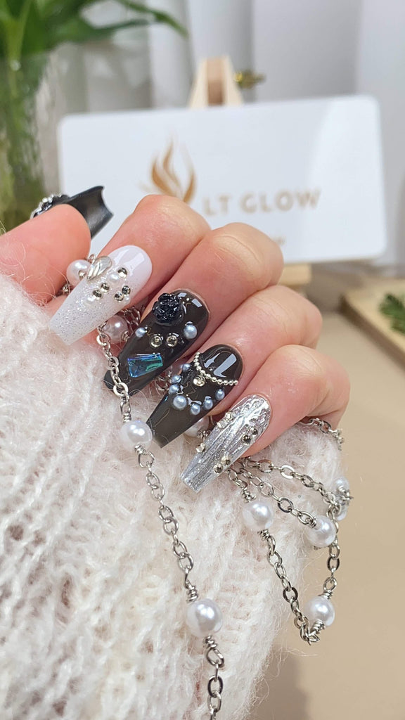 Handmade press-on nails by LTGlow in a coffin shape, adorned with pearl charms, crystals, and a gradient of black beauty to white silver