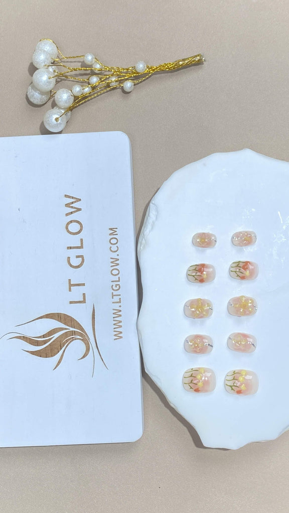 Round-styled fake nails from LTGlow, featuring a soft pink palette, enhanced by intricate flower designs and charming accents, perfect for a floral touch