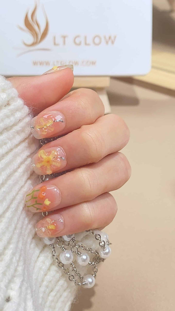 Handmade round press-on nails by LTGlow, showcasing a delicate pink hue adorned with charming flower motifs for a fresh and feminine look