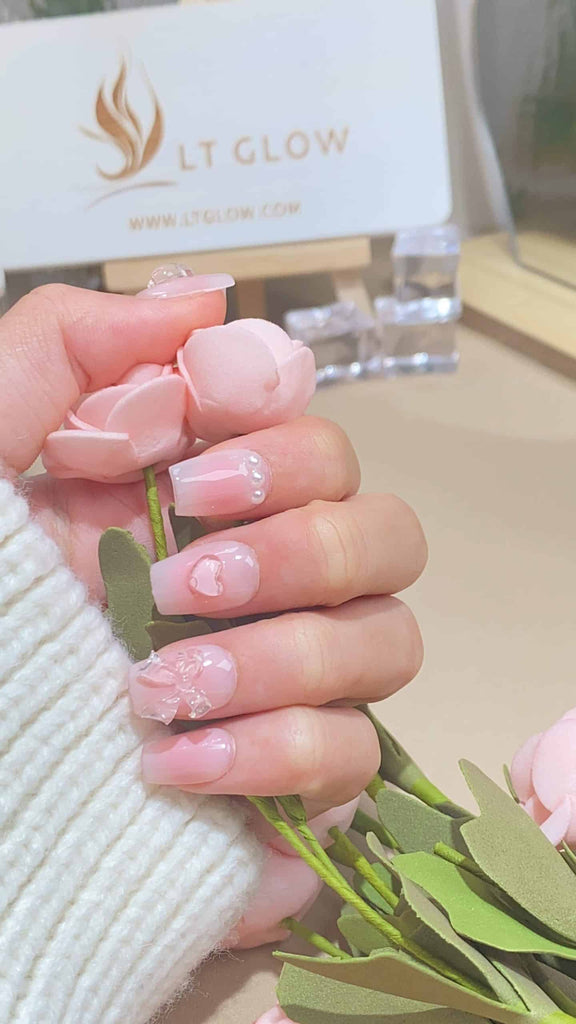 Elegant square press-on nails by LT-Glow in a soft pink shade adorned with shimmering crystals and pearls, meticulously handcrafted