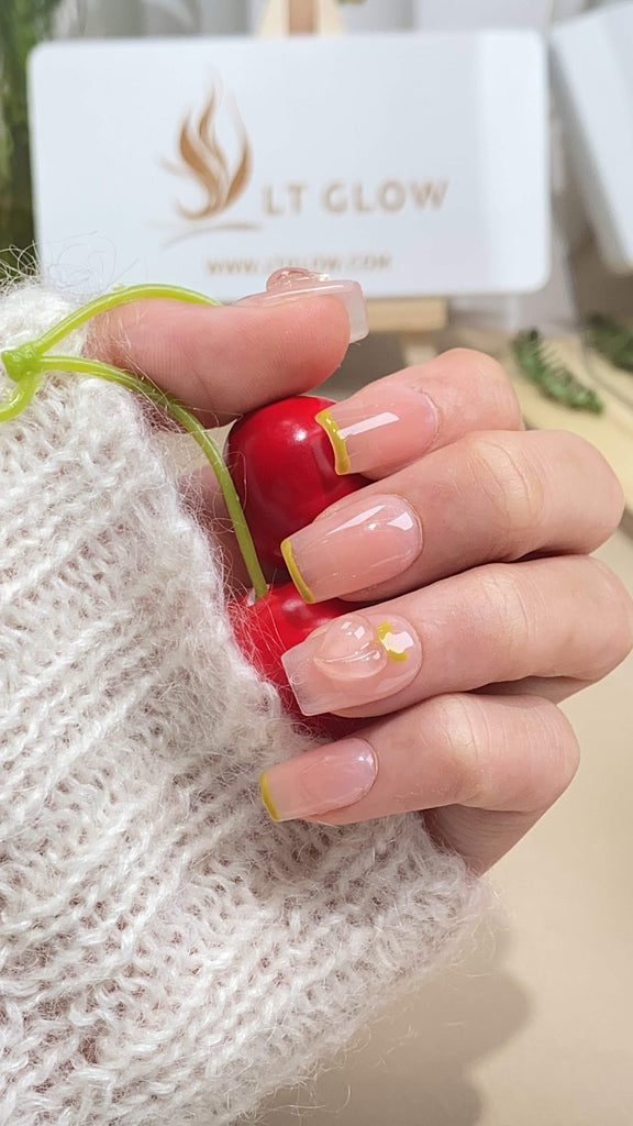Handmade squoval press-on nails by LT-Glow, blending warm hues of pink and yellow, enhanced with shimmering diamond embellishments and soft peach accents