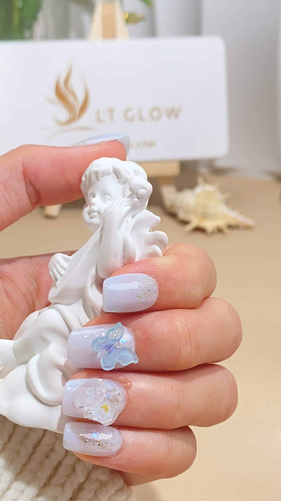 Elegant white squoval press-on nails by LT-Glow adorned with delicate butterfly and diamond accents, masterfully handcrafted