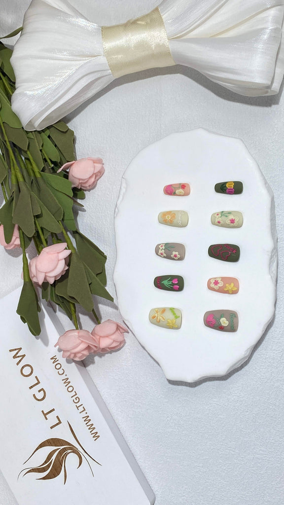 Artistic fake nails by LT Glow in a coffin shape, beautifully adorned with hand-painted flowers and angels in gray, pink, green, and white
