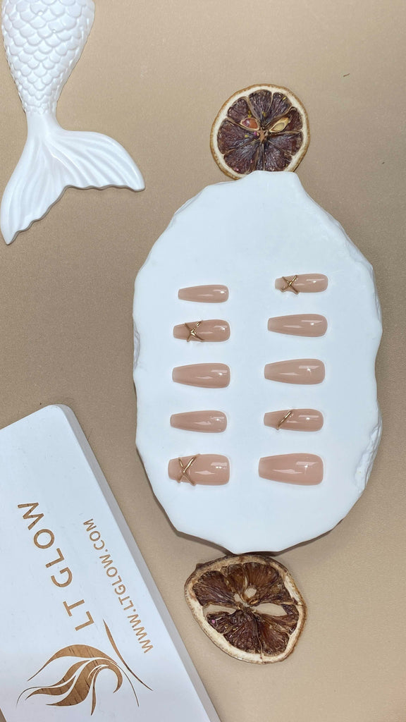 Elegant nude fake nails by LT Glow, set in a coffin silhouette, adorned with 3D features and intricate charms
