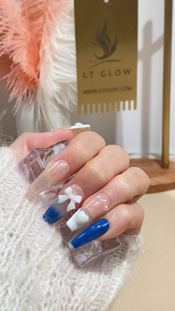 LT Glow's handcrafted coffin-shaped press-on nails in nude and blue, adorned with 3D elements, charms, French bow, heart, and pearl details