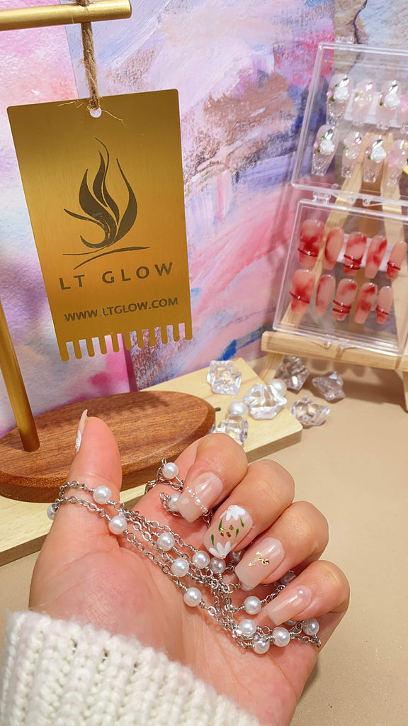 Elegant fake nails by LT Glow, showcasing a meticulously handcrafted square design in a neutral nude tone, adorned with intricate hand-painted leaf and flower motifs and elegant pearl embellishments.
