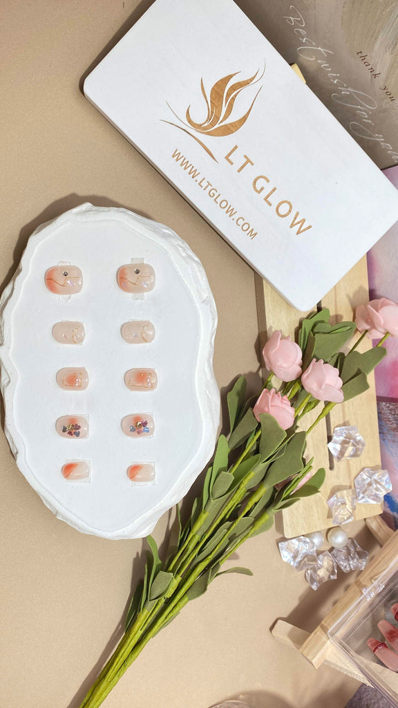 LT Glow's round-shaped press-on nails in a tasteful combination of nude and pink, featuring hand-painted glitter and lustrous pearl embellishments for a stylish look.