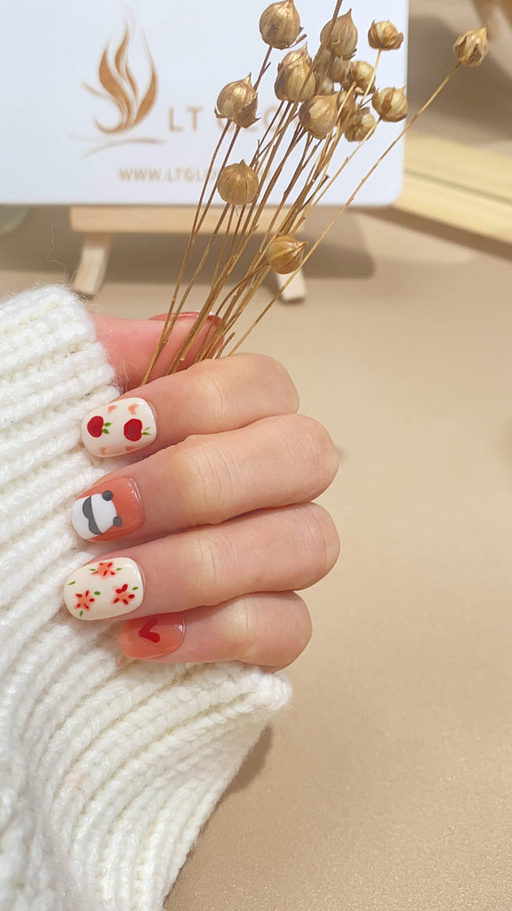 Embrace a playful elegance with these round press on nails, hand-painted with delicate pink and white hues and adorned with a cute bear and floral designs, perfect for those seeking unique acrylic nails design