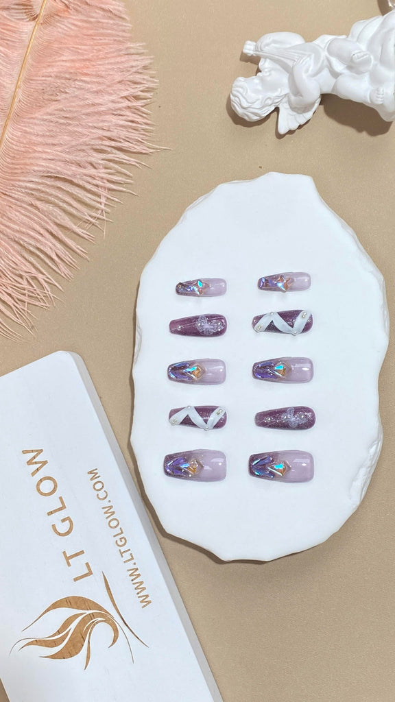 Artisanal purple press-on nails featuring intricate hand-painting and delicate pearl adornments, showcasing the beauty of coffin-style nails