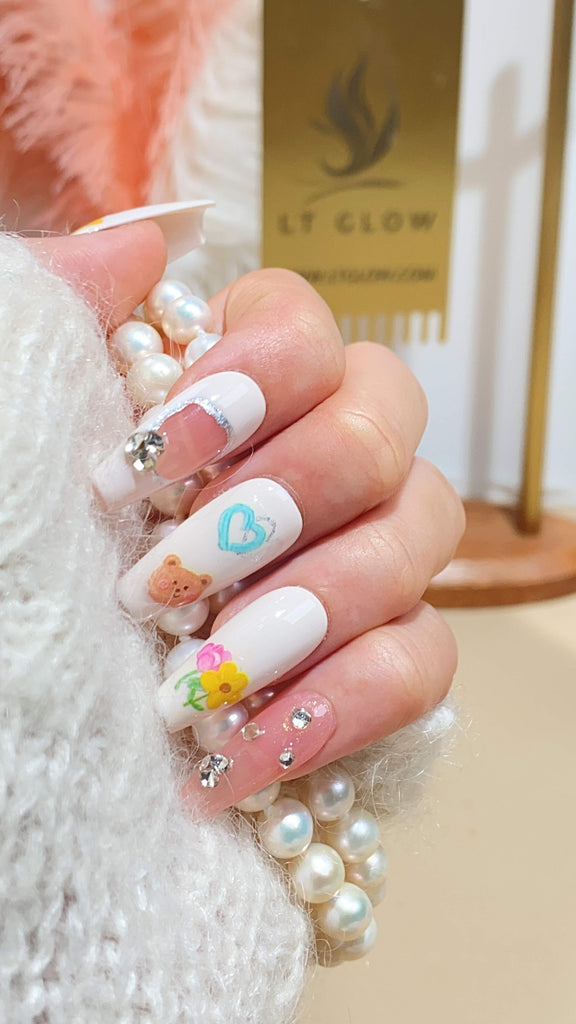 LT Glow's hand-painted coffin-shaped press-on nails blending white and pink hues, adorned with bear, heart, and flower charms
