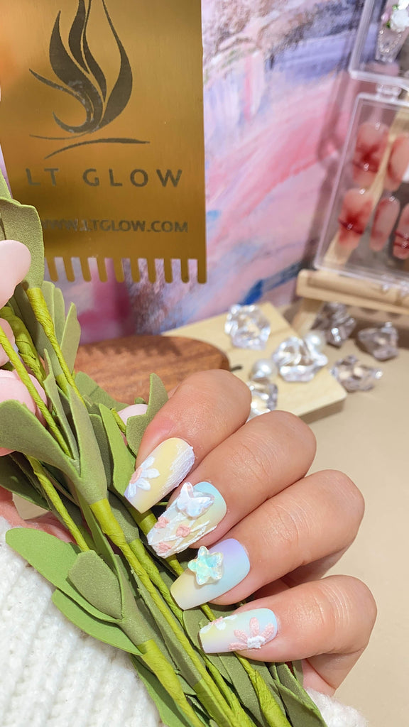 Handmade false nails from LT Glow, presenting a charming coffin shape in yellow and purple, complemented by whimsical star, moon, and butterfly hand-painted artistry, crafted with precision.